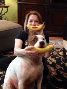 a woman holds a banana in front of a dog 's mouth