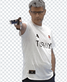 a man wearing a white shirt that says turkey is pointing a gun