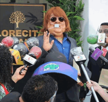 a man wearing sunglasses and a mask is surrounded by microphones and a sign that says orecita