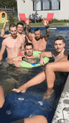 a group of men are swimming in a pool and one of them is wearing a green float that says ' a '