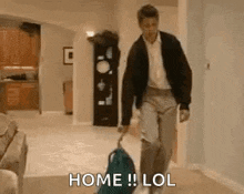 a man is walking with a suitcase in a living room and says `` home lol '' .