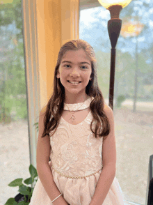 a little girl in a white dress with the letter r on her neck smiles for the camera