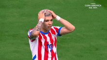 a soccer player covering his face with his hands in front of a screen that says copa america usa 2020