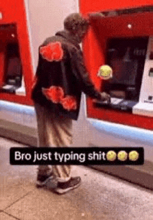 a man is standing in front of an atm machine holding a tennis ball .