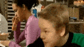 a boy and a girl are sitting at a table in a kitchen . the boy is wearing a green shirt .