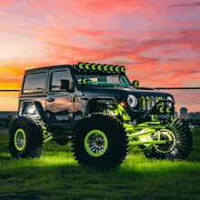 a black jeep is parked in a grassy field with a sunset in the background