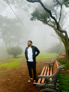 a man standing next to a wooden bench in the fog