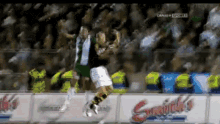 a soccer player is jumping in the air in front of a stadium full of people ..