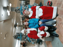 three people dressed as santa claus pose for a photo