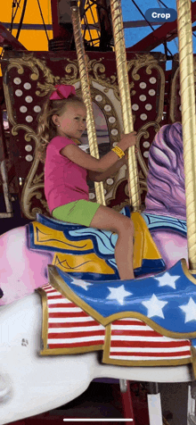 a little girl is sitting on a merry go round with a crop button on the bottom