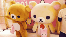 two teddy bear mascots are standing next to each other in front of a pink sign .