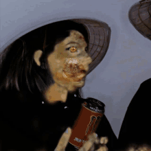 a woman in a hat holds a can of monster energy drink