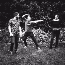 a black and white photo of three people standing in a grassy area