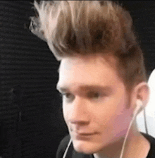 a young man wearing headphones and a mohawk is looking at the camera .