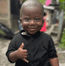 a little boy is smiling and giving a thumbs up .