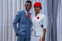 a man in a suit and tie and a woman in a white dress are posing for a picture together .