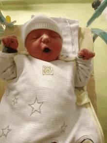 a newborn baby wearing a winnie the pooh outfit with stars