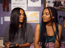 two girls sit next to each other in front of a poster that says hugs smiles and warm fuzzy feelings