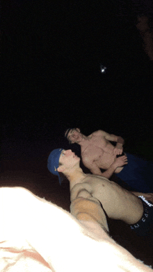 a shirtless man in a blue hat is standing next to another shirtless man in blue shorts