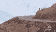 a car is going down a road on a hill .