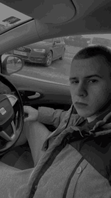 a black and white photo of a man driving a seat