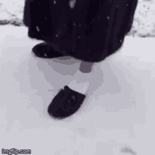 a person wearing slippers and white socks is walking through the snow .