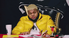 a man in a yellow jacket sits in a chair