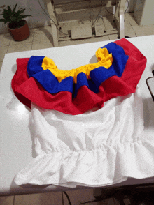 a white shirt with red yellow and blue ruffles on the shoulder