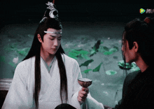 a man in a white kimono is holding a bowl in front of a man in a black kimono