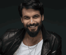 a man with a beard wearing a leather jacket and a white shirt