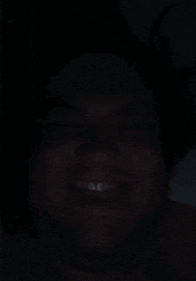 a close up of a person 's face in the dark with a smile on their face .