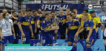 a group of soccer players are posing for a picture with a trophy in front of a sign that says futsal