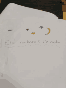 a piece of paper with a drawing of a moon and stars and the words eid mubarak sio madan