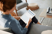 a woman sits on a couch using a tablet with a screen that says ' i 'm sorry '