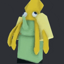 a yellow and green squid with big eyes is standing on a green box .