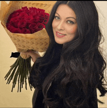 a woman is holding a bouquet of red roses in a wrapping that says " love "