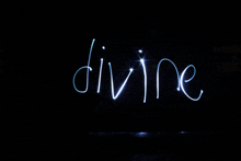 the word divine is written with light in the dark