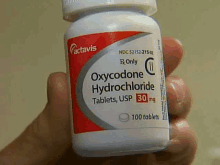 a person holds a bottle of oxycodone hydrochloride tablets