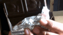 a person holding a piece of aluminum foil with the letter n on it