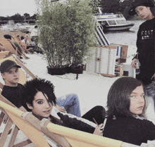 a group of young people sitting on a beach with one wearing a shirt that says k & n