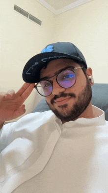 a man with a beard wearing glasses and a hat with arabic writing