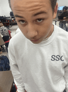 a boy wearing a white sweatshirt with the word ssc on the front