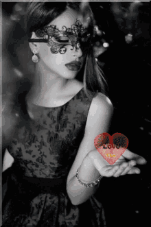 a woman wearing a mask is holding a red heart that says love on it