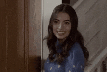 a woman in a blue sweater is standing in a doorway looking at the camera .