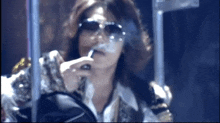 a woman wearing sunglasses smoking a cigarette