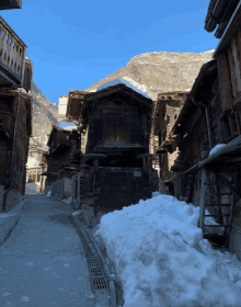 a snowy street with a mountain in the background and a few buildings