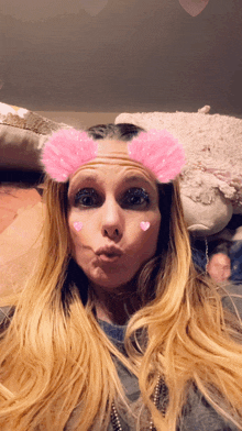 a woman with long blonde hair and pink hearts on her face makes a funny face