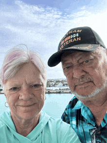 a man wearing a vietnam veteran hat stands next to his wife