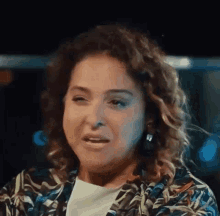 a woman with curly hair is making a funny face while wearing a floral jacket .