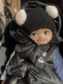 a baby wearing a black and white hat and a black jacket